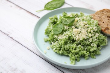 Tasty spinach risotto served with bread on white wooden table, closeup. Space for text
