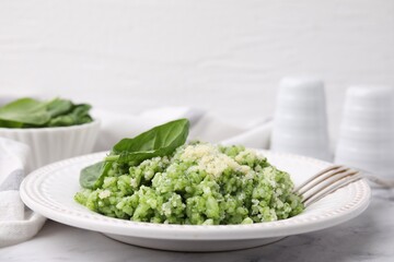 Tasty spinach risotto served on white marble table, closeup