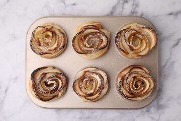 Freshly baked apple roses on white marble table, top view. Puff pastry