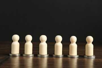 Financial equality. Wooden figures with similar quantity of coins on table. Space for text