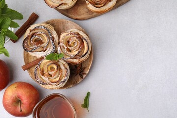 Freshly baked apple roses, ingredients and tea on light table, flat lay. Space for text