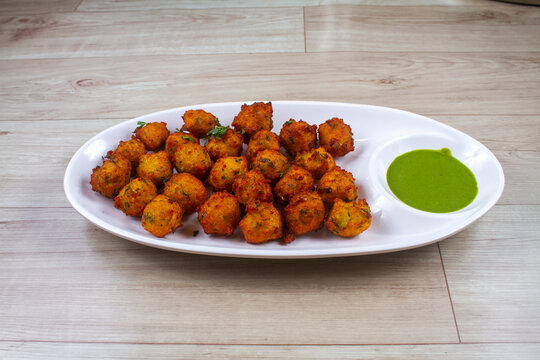 moong pakoda or bhaji of Popular indian street food snack on wooden background, Diwali dinner or iftar meal, Dish for christmas party.