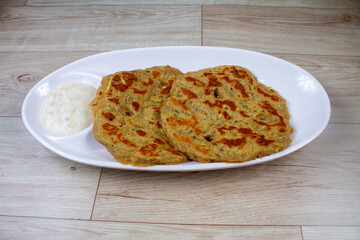Potato Stuffed Flat Bread or Aloo paratha is a Traditional Indian food. served with curd, butter or ghee. selective focus. isolated on yellow background.
