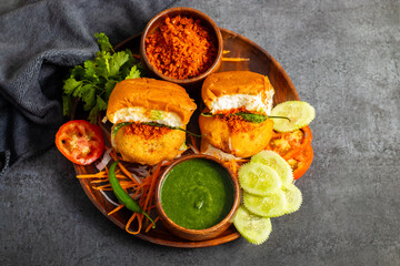 selective focus of Mumbai's famous street food delicious Vada Pav, With coriander leave chutney, tomato sauce, dry garlic chutney and fried chilli. 