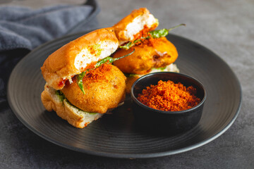 selective focus of Mumbai's famous street food delicious Vada Pav, With coriander leave chutney,...