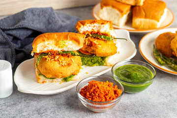 selective focus of Mumbai's famous street food delicious Vada Pav, With coriander leave chutney, tomato sauce, dry garlic chutney and fried chilli. 