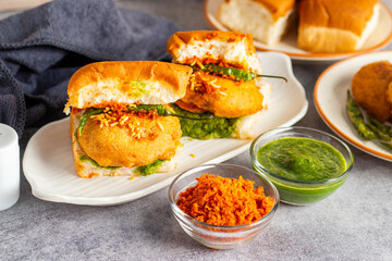 selective focus of Mumbai's famous street food delicious Vada Pav, With coriander leave chutney, tomato sauce, dry garlic chutney and fried chilli. 