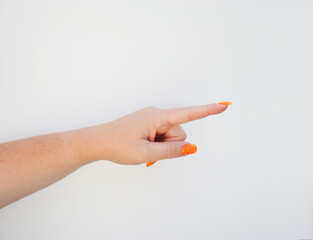 woman hand pointing with orange nails on white background