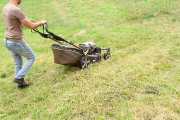 man cutting the grass with black lawnmower