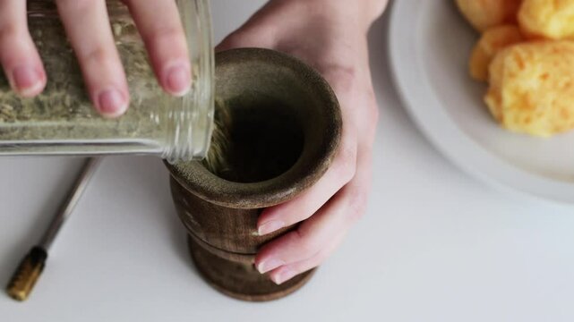 Preparing a popular breakfast in South America: Mate with Chipa, which is a type of infusion and small, baked, cheese-flavored rolls. First step, fill the cup with yerba mate