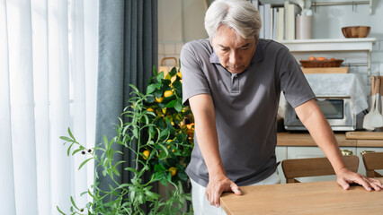 Elderly Asian man suffering from accumulated stress, headache, unable to stand, using hands to...