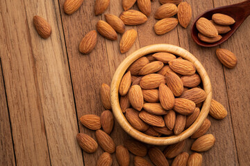 Dry roasted Almonds in wooden bowl on wooden table.Heap of almond.with copy space.Top view