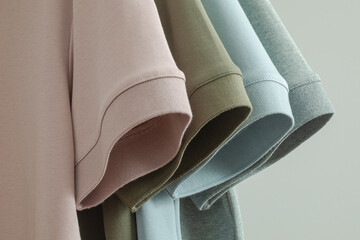 Close up view of sleeves of four men's cotton polo shirts in different colors