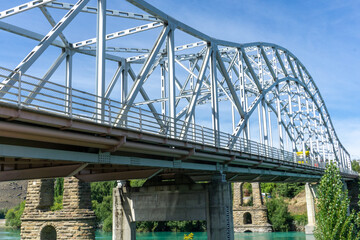 Historic bridge ruins over the Clutha River in Alexandra, New Zealand. Surrounded by the striking blue waters and lush greenery of Otago, nature lovers photographers exploring South Island