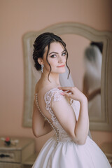 Fototapeta premium A woman in a white dress is posing for a picture. She is wearing a necklace and earrings