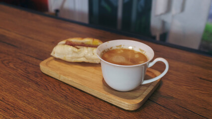 Morning hot Coffee with Cappuccino and vietnamese bread served on Wooden Tray,  placed on rustic wooden table by Window with natural view. Food and drink concept.