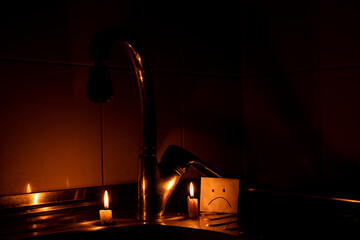 Candles near the kitchen faucet on the sink and a sad emotion on paper drawn in an apartment in...