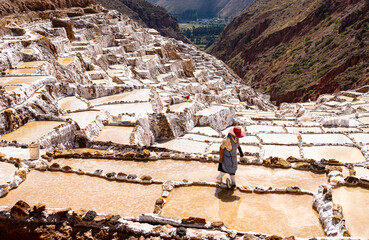 Mujer caminando dentro de las piscinas de Sal de las salineras de Maras, Urubamba, Cusco. Perú.