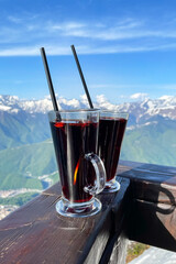 Two glasses with mulled wine on a background of mountains close-up.