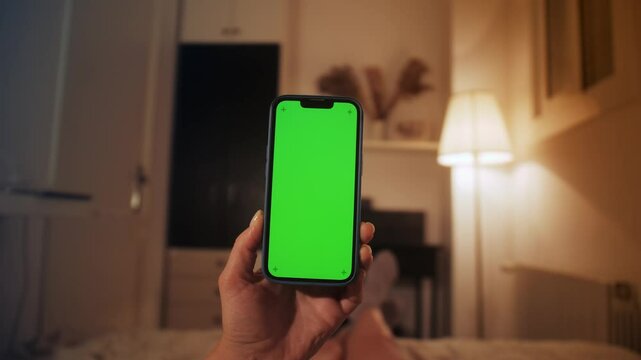 Person holding green screen smartphone. Girl watching video reading e-book while looking at mock up screen.