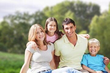 Fototapeta premium Cheerful young family sitting on the park.