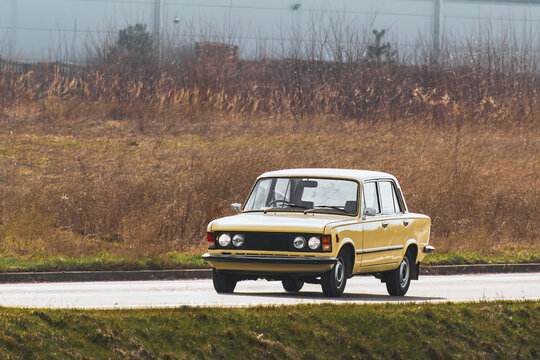 Fototapeta Classic yellow sedan driving through countryside