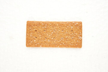 the image of the thin, rectangular coffee biscuit with a sugar coating on a white surface.