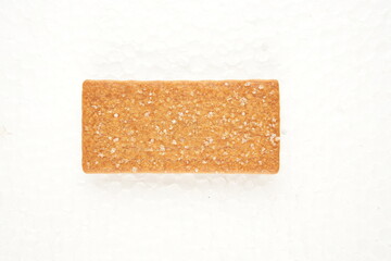the image of the thin, rectangular coffee biscuit with a sugar coating on a white surface.