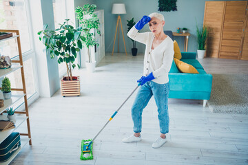 Photo of attractive tired senior woman wear white cardigan doing cleaning routine indoors room home house