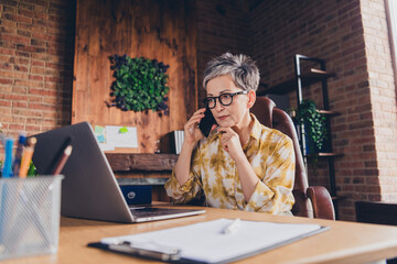 Photo of lovely pensioner lady talk phone working netbook thoughtful dressed formalwear comfortable...