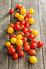 Different colorful cherry tomatoes on wooden table.