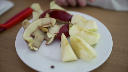 Sliced apple and peels on a white plate, showcasing the natural and wholesome goodness of fresh fruit prepared for a healthy snack