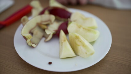Sliced apple and peels on a white plate, showcasing the natural and wholesome goodness of fresh fruit prepared for a healthy snack