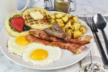 fried eggs with sausage , bacon and waffles