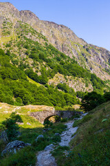 Petit pont de pierre enjambant le Neste d’Oô depuis le Lac d’Oô dans  dans les Pyrénées à côté de Bagnères-de-Luchon