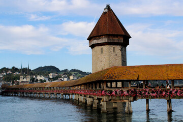 Wooden bridge with an orange rooftop and a tower over a lake