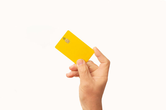 Mano de hombre sosteniendo una tarjeta con chip de cr&eacute;dito de color amarillo en un fondo blanco liso y aislado. Vista de frente. Copy space. Concepto de negocios y finanzas