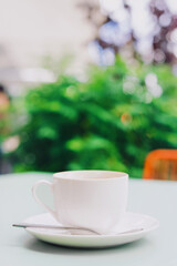 A white mug with a saucer from which they drank coffee outside. Summer terrace