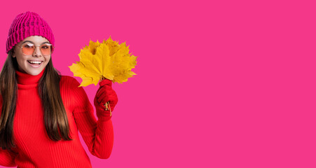 Autumnal season. Fall fashion. Happy young girl playfully hold yellow maple leaves. Teen girl with...