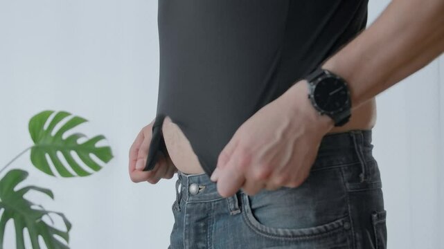 A man with a big abdomen putting on a shirt to seem a little bit thin.