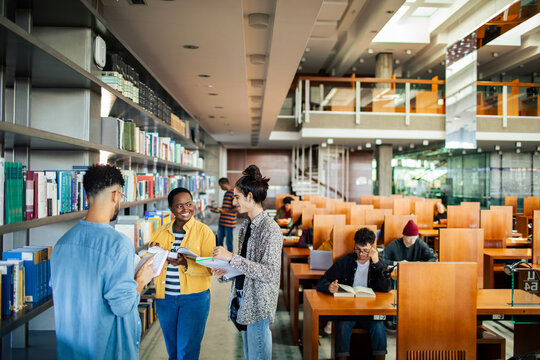 Diverse students picking books in college library