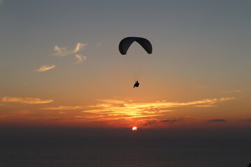 Paraglider silhouette over pretty red sunset in Torrey Pines San Diego