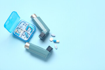 Fototapeta premium Asthma inhalers and box with pills on blue background