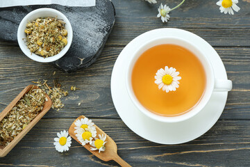 Cup of hot chamomile tea on dark wooden background