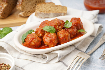 Plate of tasty meat balls with tomato sauce and basil on grey table