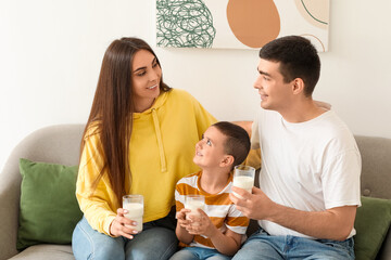 Little boy with his parents drinking milk on sofa at home