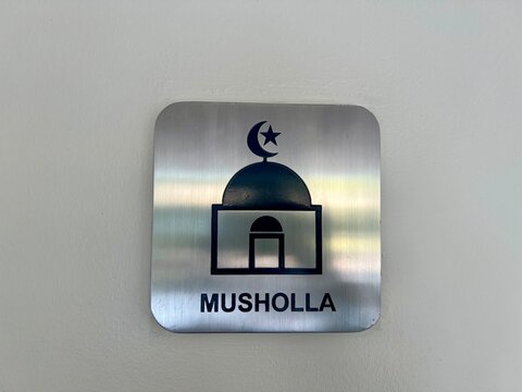 Closeup photo metalic plate sign instaled on white wall. Photo of ap place for praying for moeslem isolated in white