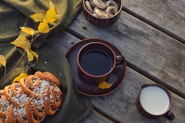 Swedish cinnamon bun and coffee on wooden table in nature. Autumn time