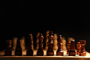 Game board with wooden chess pieces on dark background, closeup