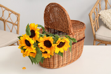 Wicker basket with sunflowers on table in dining room